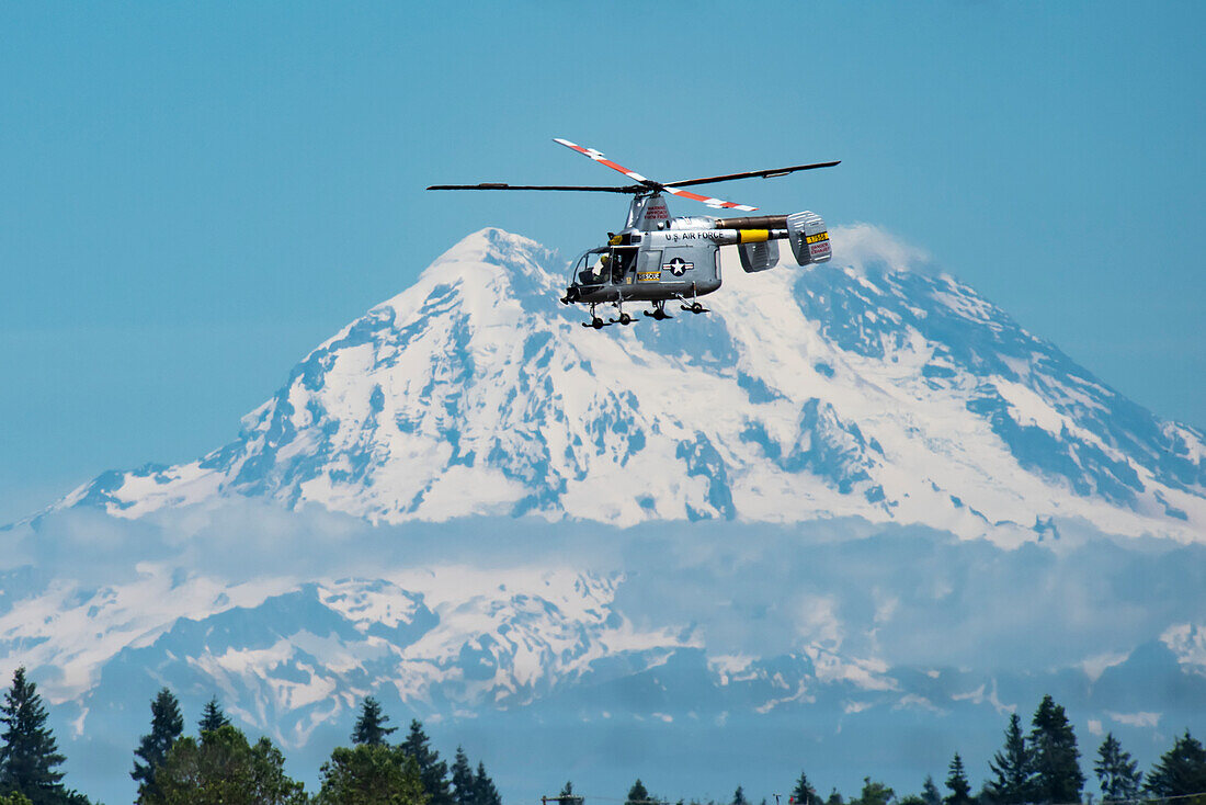 Kaman HH-43F Huskie Helicopter, owned by the Olympic Flight Museum, performing aerobatic manoeuvres with Mount Rainier in the background, 2019 Olympic Air Show, Olympic Airport; Olympia, Washington, United States of America