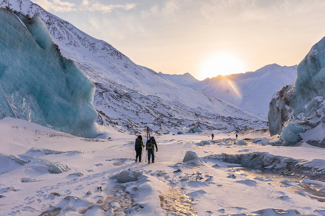 Winterwanderer erkunden den Black Rapids Glacier, während die Sonne über der Alaska Range untergeht; Alaska, Vereinigte Staaten von Amerika