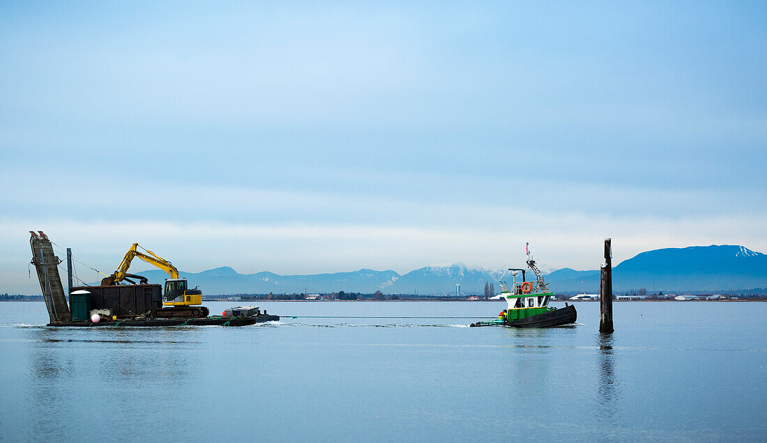 Tugboat pulling barge with construction equipment, Blackie Spit, Crescent Beach; Surrey, British Columbia, Canada