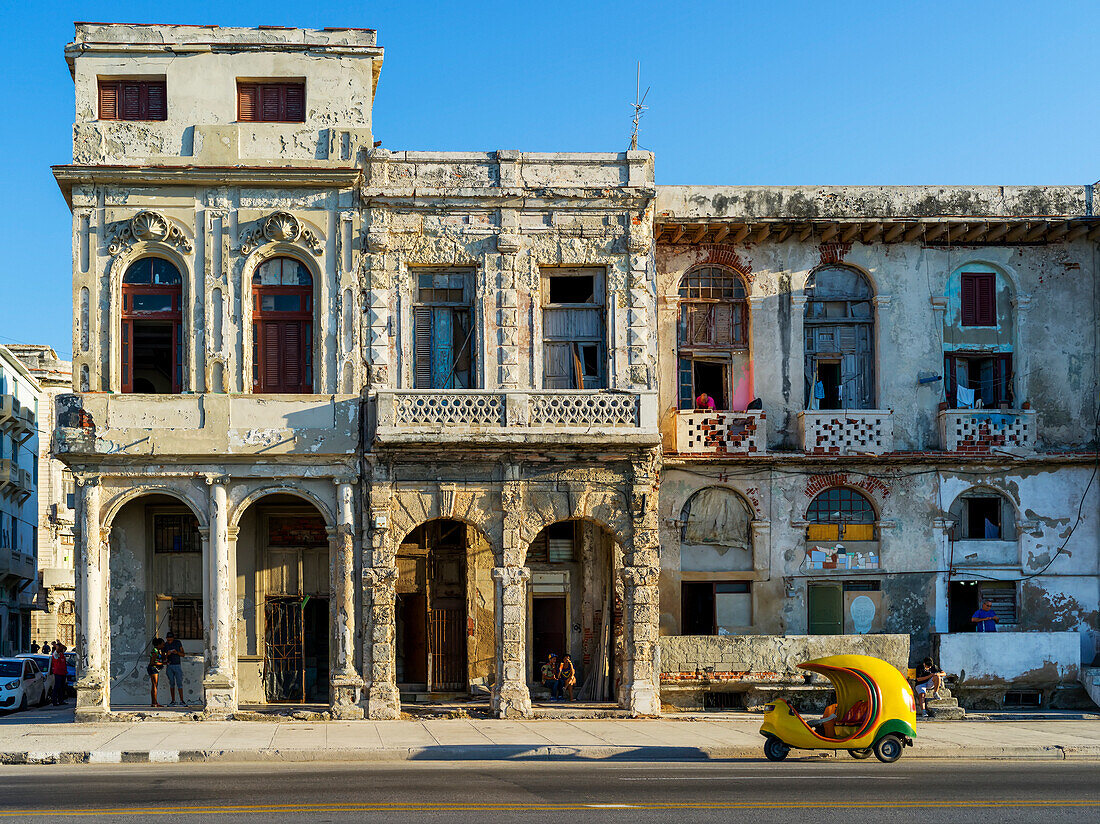 The weathered facade of a residential building along a street; Havana, Cuba