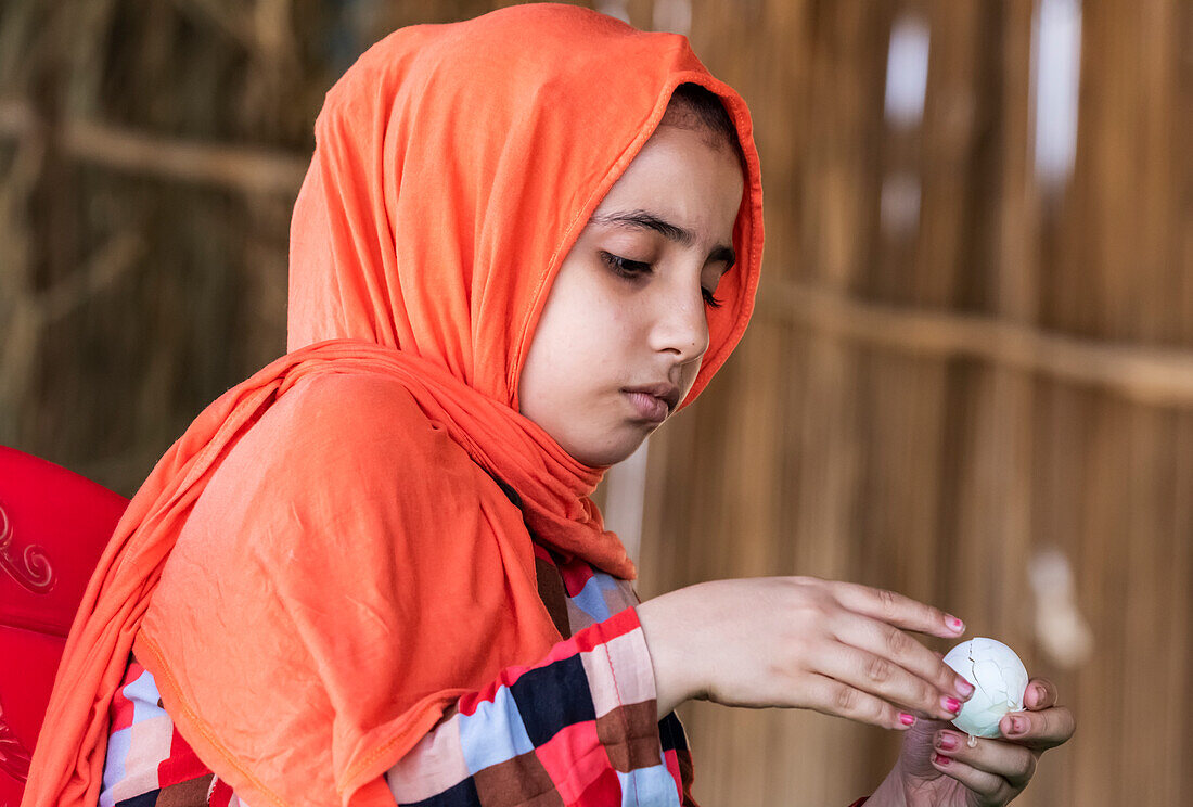 Sudanesisches Mädchen schält ein gekochtes Ei; Al Huqnah, Khartum, Sudan