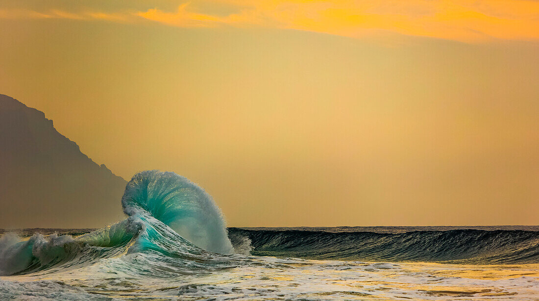 Ocean waves crashing into the shore off the Na Pali coast at sunset; Kauai, Hawaii, United States of America