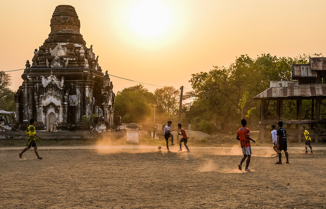 Boys playing football at sunset; Bagan, Mandalay Region, Myanmar