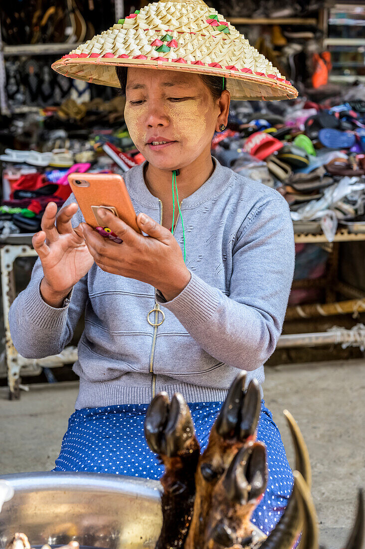 Woman on her smartphone at the market; Lashio, Shan State, Myanmar