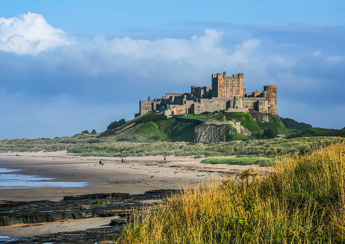 Bamburgh Castle with the tide out showing rocky coastline; Bamburgh, Northumberland, England