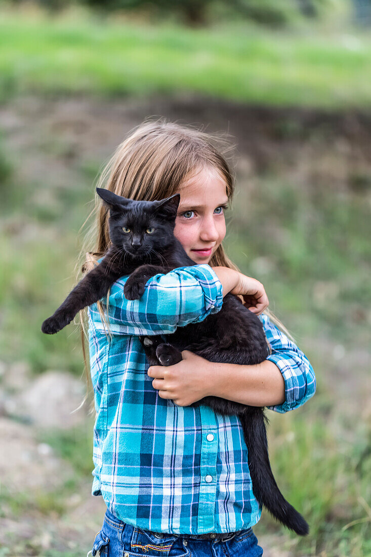 Junges Mädchen mit Farmkatze; Armstrong, British Columbia, Kanada