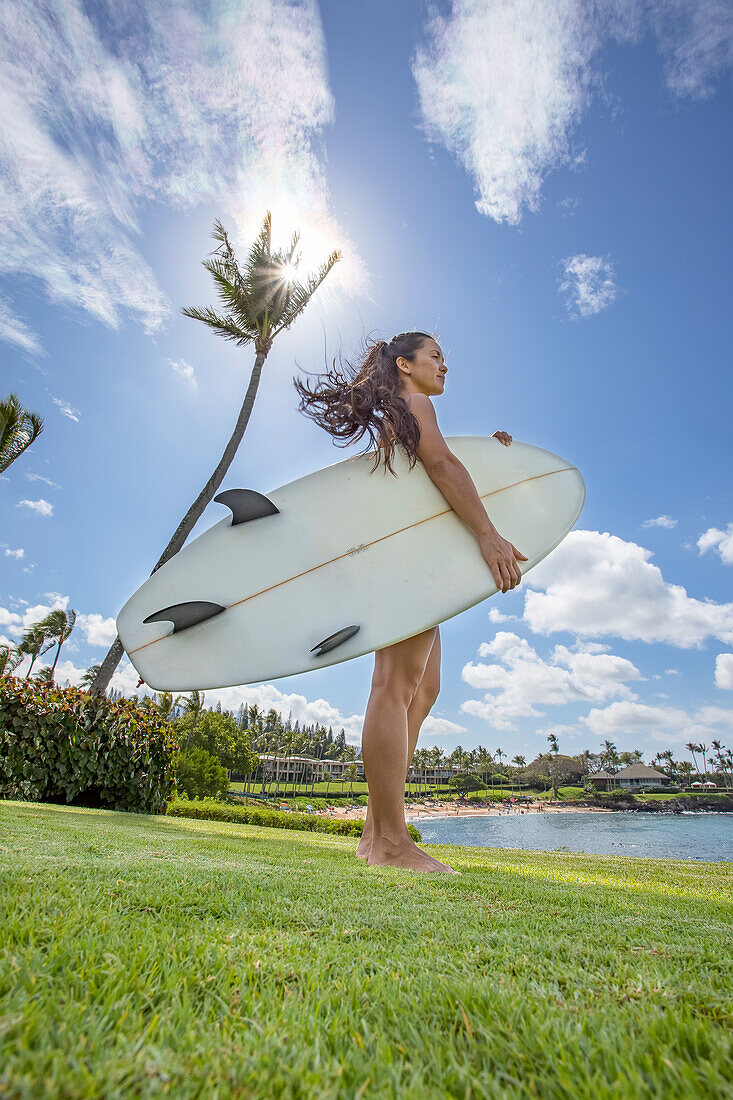 A young woman with surfboard at Kapalua Bay and beach; Maui, Hawaii, United States of America