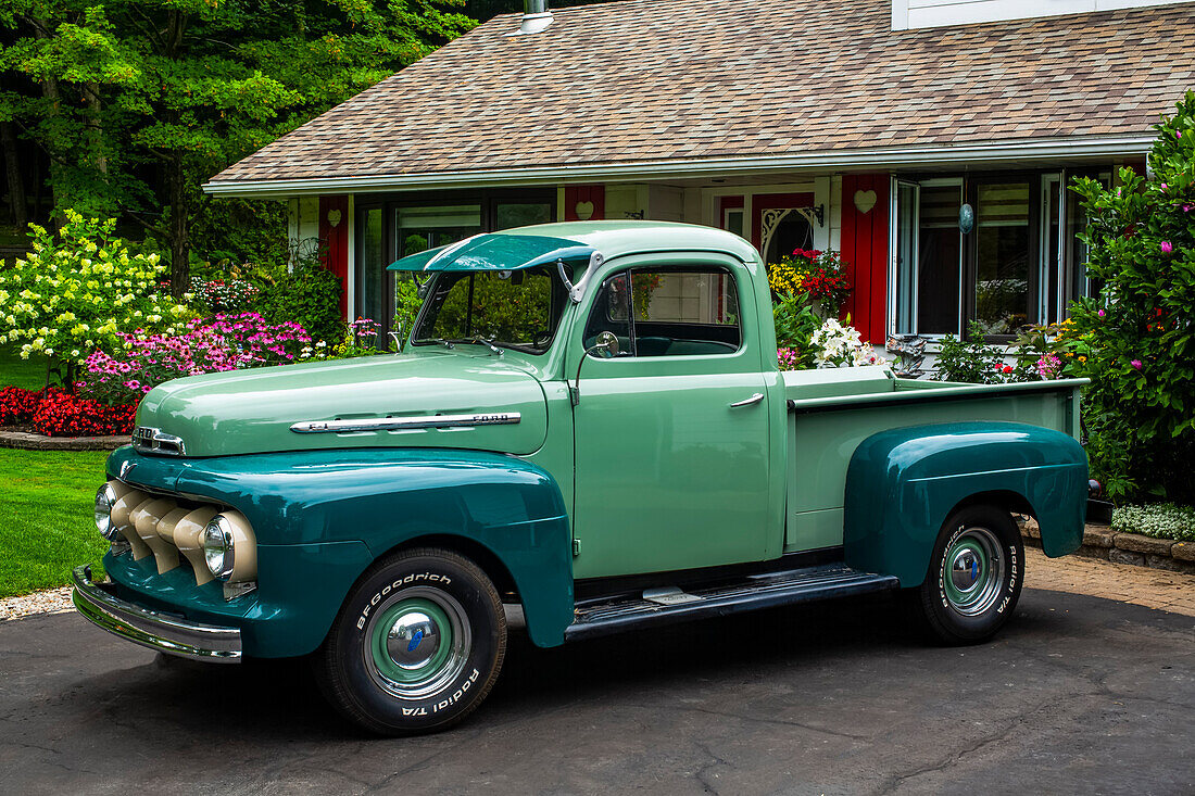 Vintage truck parked outside a house with blossoming flowers; Hudson, Quebec, Canada