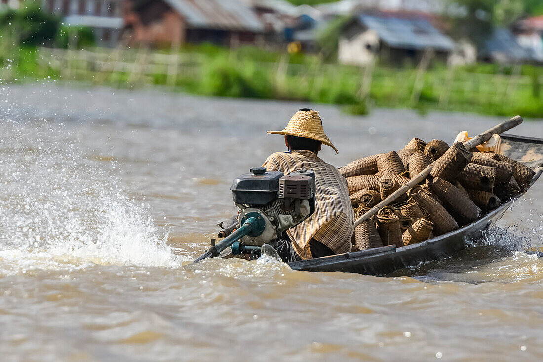 A man drives a motorboat in Inle Lake to transport goods; Yawngshwe, Shan State, Myanmar