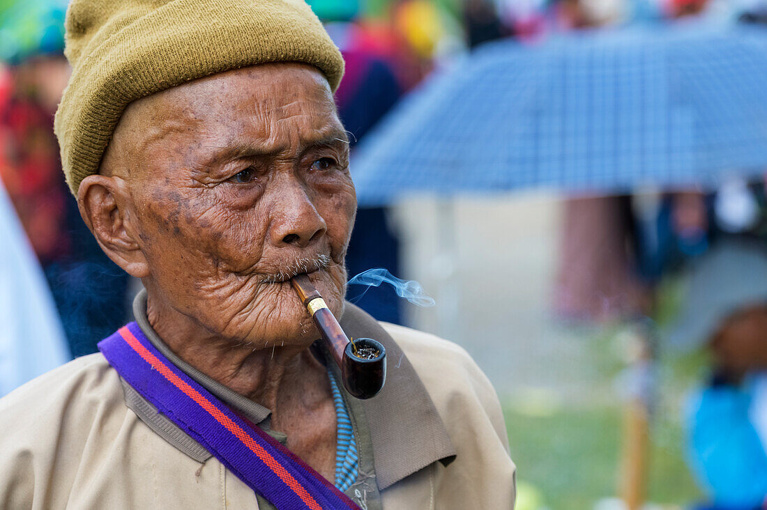 Burmese senior man smoking a pipe; Yawngshwe, Shan State, Myanmar