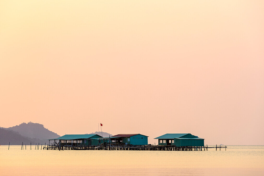 Elevated buildings on the water during a glowing pink sunset, Starfish Beach; Phu Quoc, Kien Giang Province, Vietnam