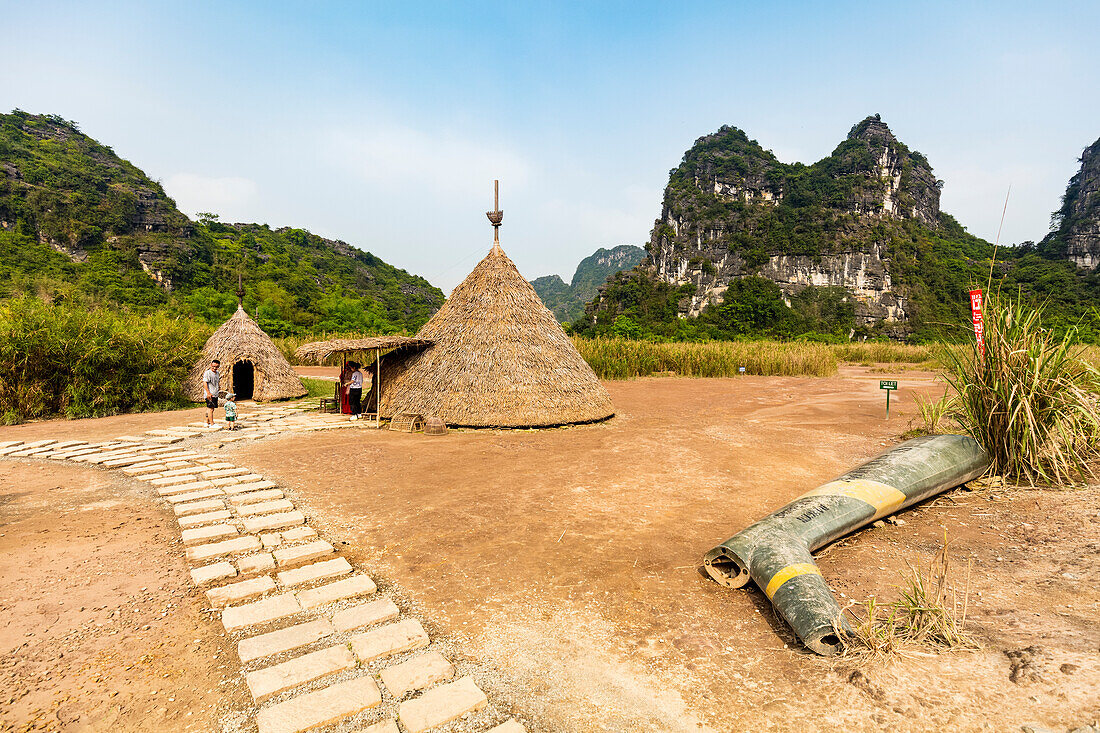 Touristen an Strohdachstrukturen und Kalksteinkarst, Ninh Binh-Landschaft; Ninh Binh-Provinz, Vietnam