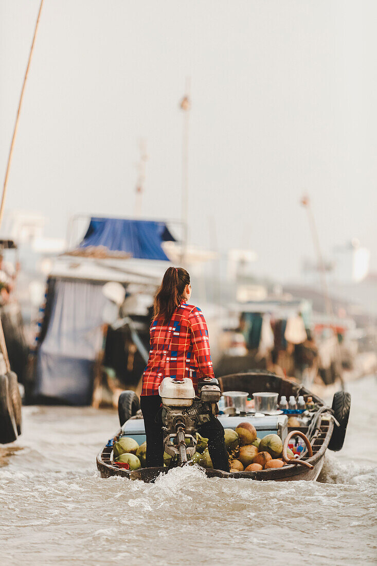 Frau transportiert frisches Obst in einem Motorboot, schwimmender Markt von Cai Rang; Can Tho, Vietnam