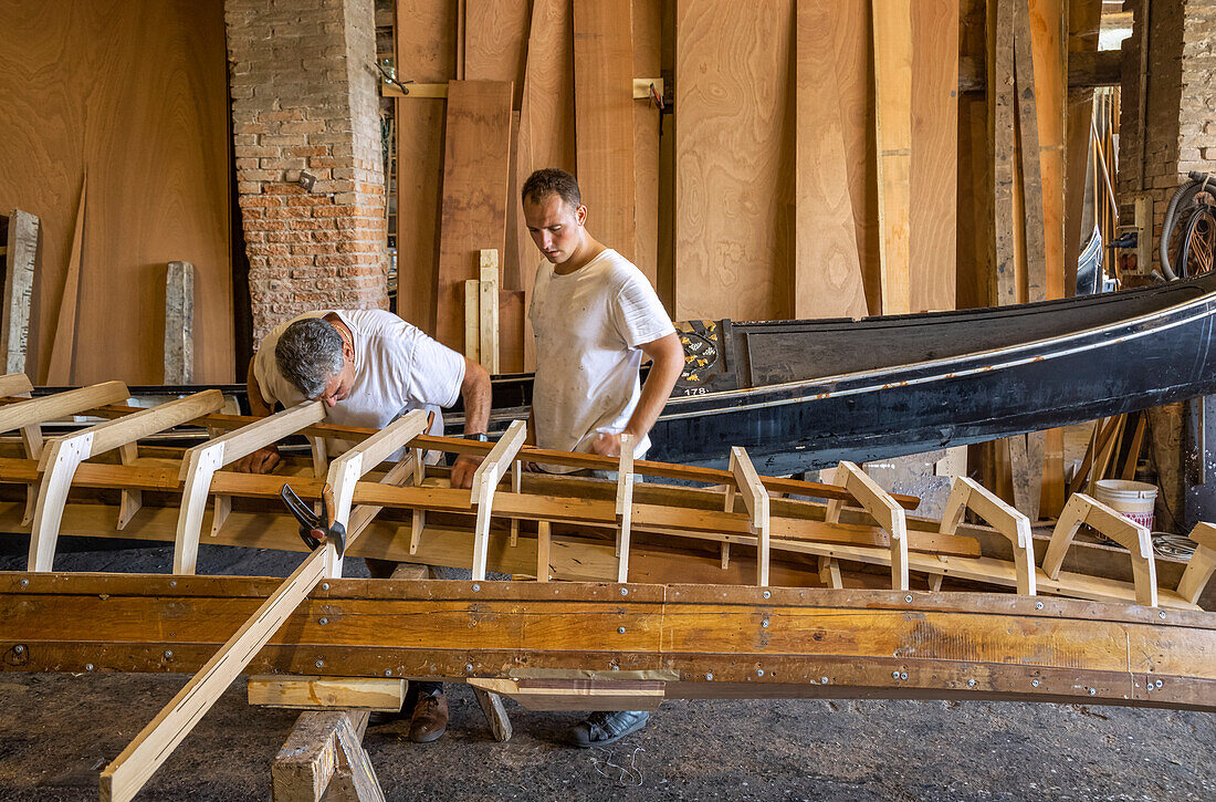 Two craftsmen working on the construction of a gondola; Venice, Italy