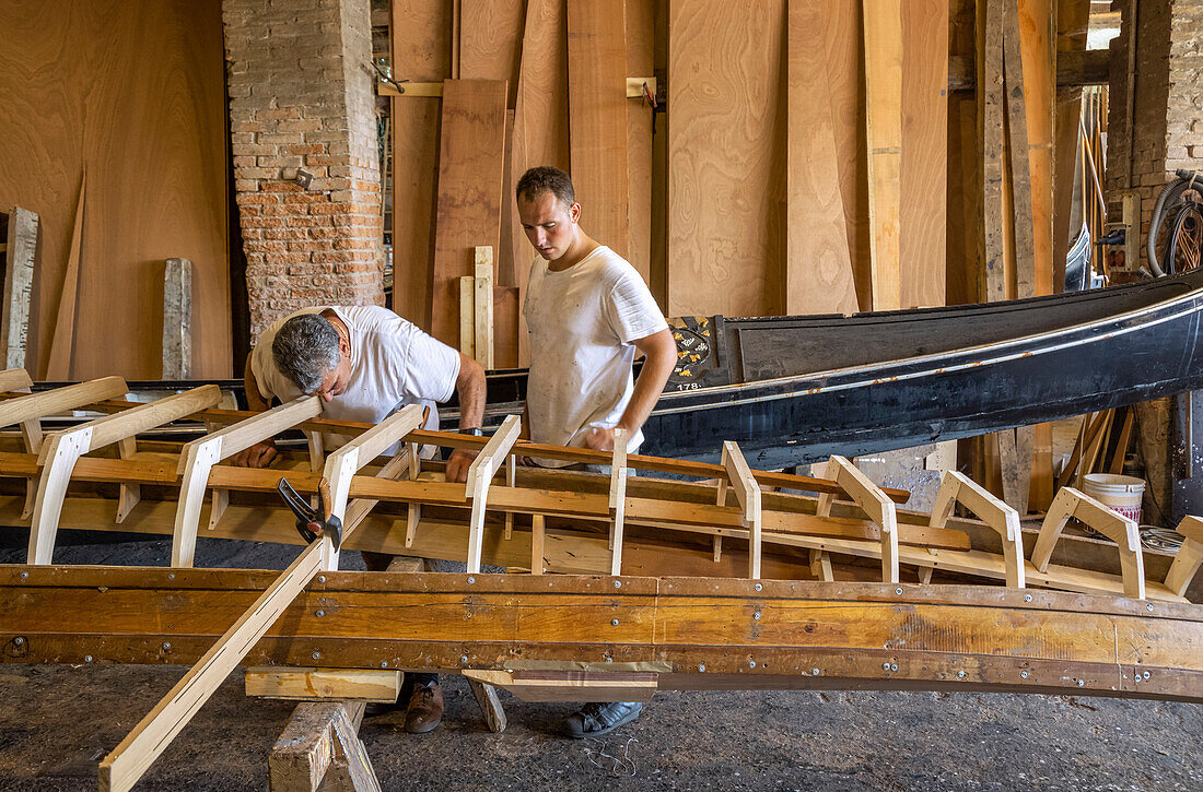 Zwei Handwerker arbeiten an der Konstruktion einer Gondel; Venedig, Italien