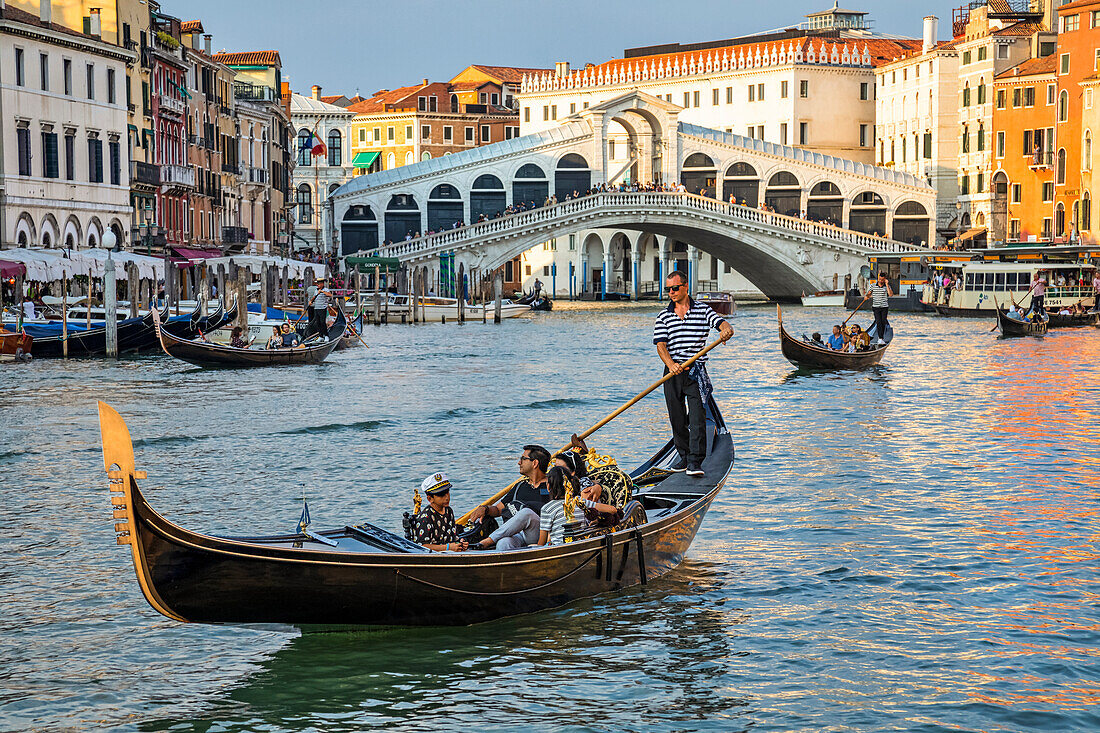 Gondeln und Gondoliere auf dem Canal Grande mit Touristen entlang des farbenfrohen Ufers; Venedig, Italien