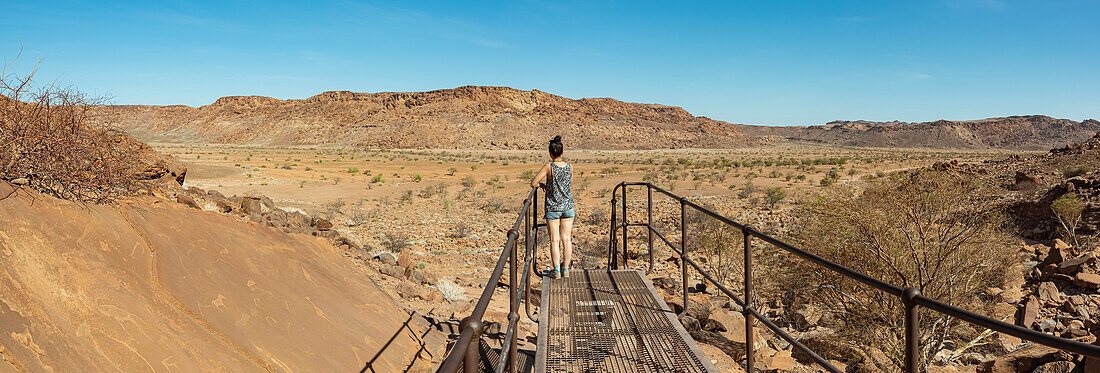 Frau steht auf einem Steg in Twyfelfontein, einer alten Felsgravurstätte, Damaraland; Kunene Region, Namibia