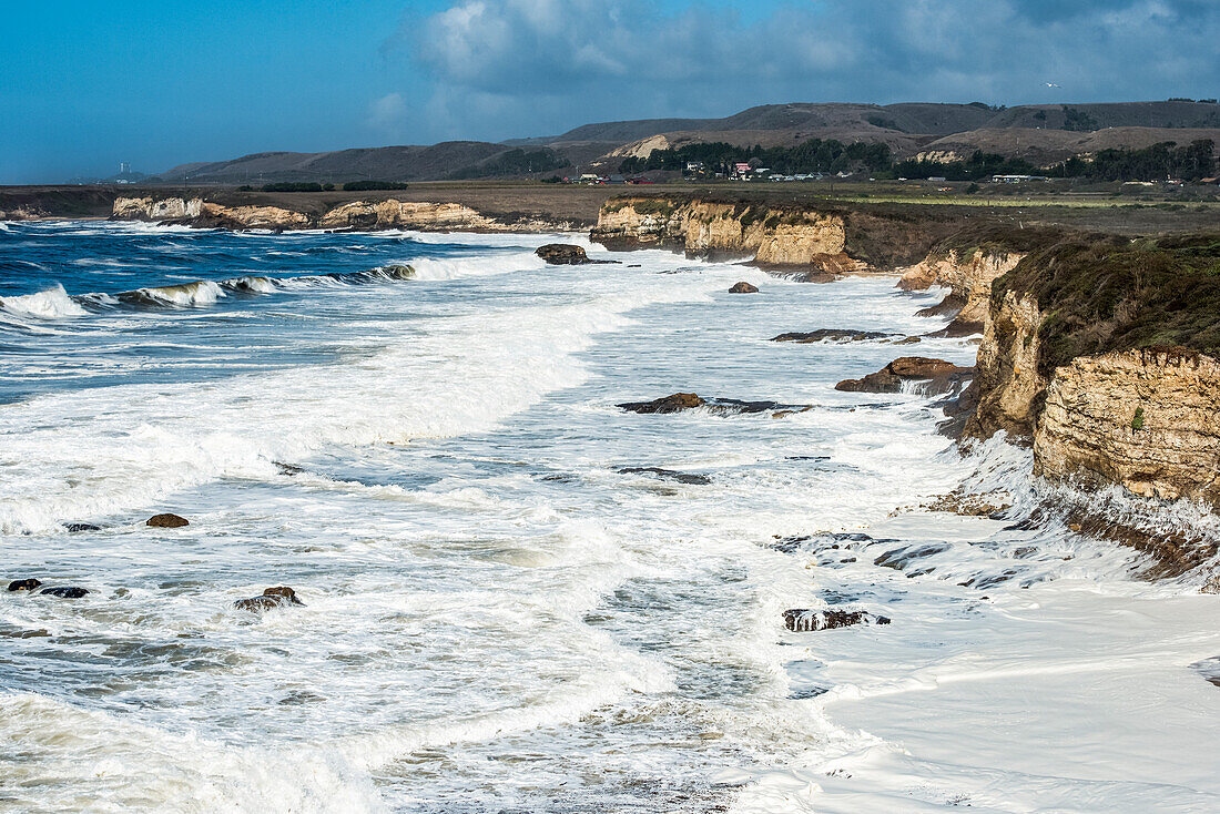 Beach foam created by waves crashing onto a beach at Wilder Ranch State Park; California, United States of America