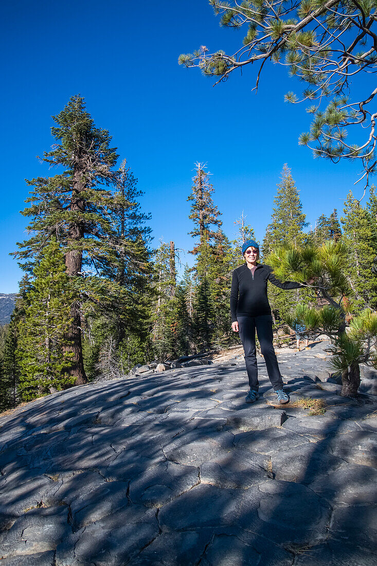 Frau steht auf gletscherpoliertem Säulenbasalt im Devil's Postpile National Monument; Kalifornien, Vereinigte Staaten von Amerika