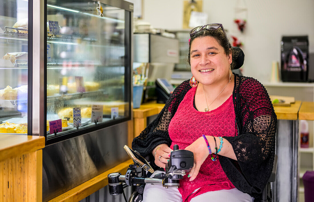 Maori woman with Cerebral Palsy in a wheelchair in a cafeteria; Wellington, New Zealand