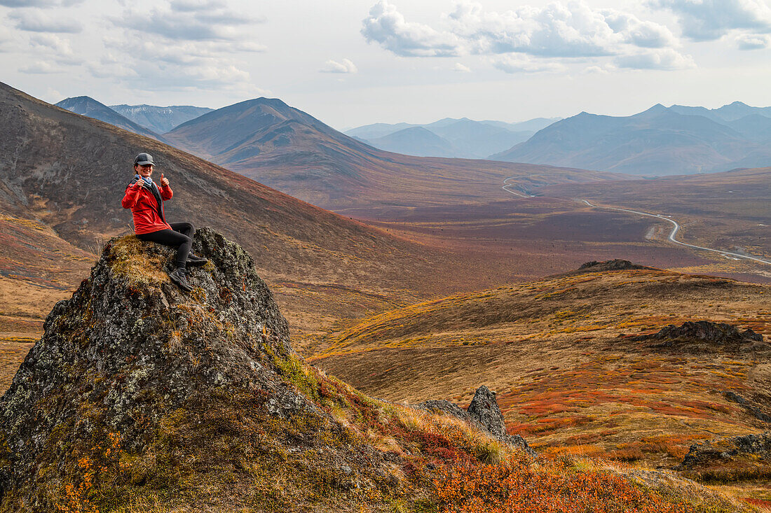 Frau erkundet die Berge entlang des Dempster Highway im Herbst; Yukon, Kanada