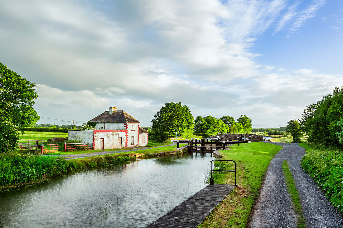 Altes rot-weißes Haus neben einer Schleuse am Grand Canal in Kildare an einem Sommerabend; Rathangan, Grafschaft Kildare, Irland