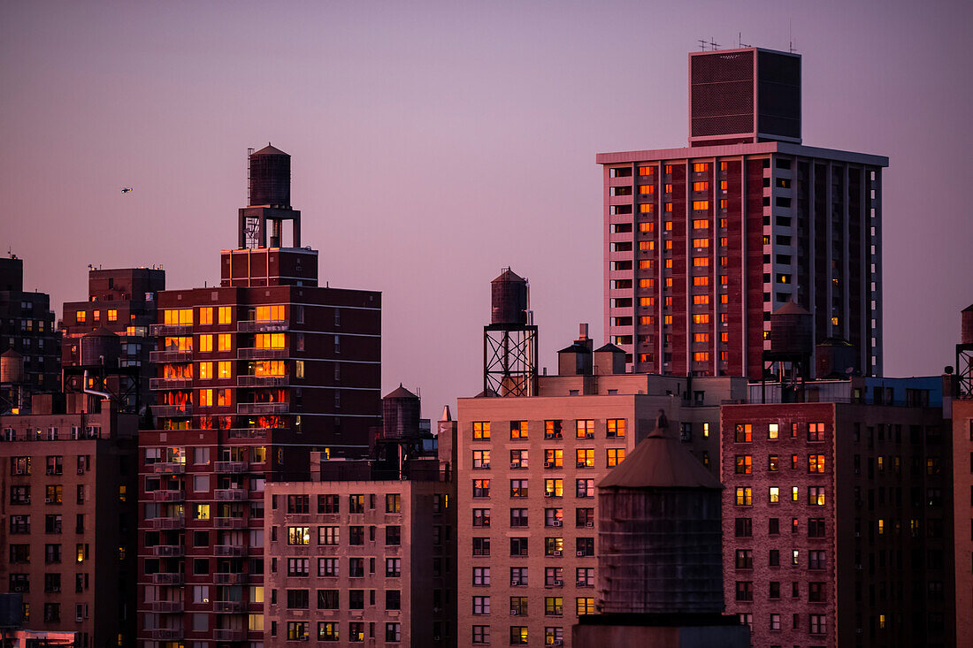 Wohngebäude in der Abenddämmerung mit HLK-Anlage und Wasserreservoirs auf den Dächern; New York City, New York, Vereinigte Staaten von Amerika