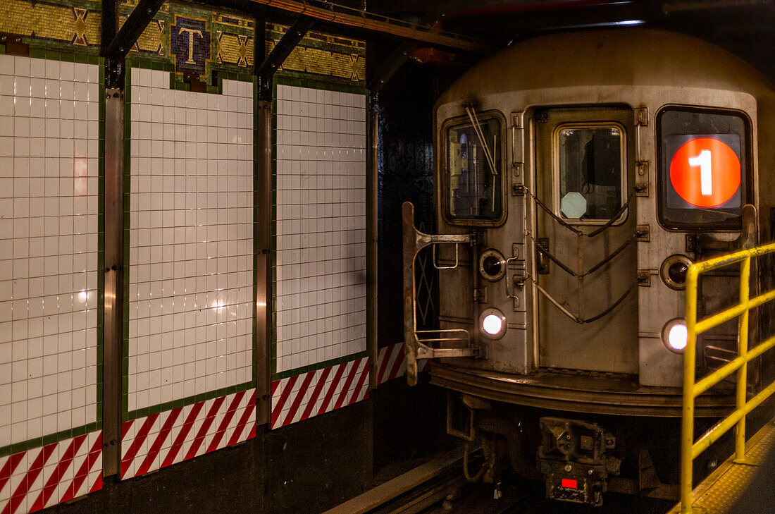 Subway underground on tracks beside tiled wall, Manhattan; New York City, New York, United States of America