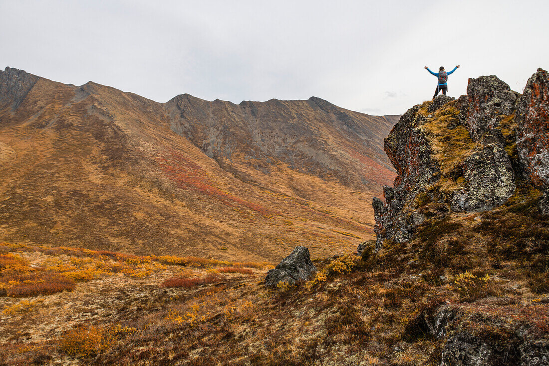 Frau erkundet die Berge entlang des Dempster Highway im Herbst; Yukon, Kanada