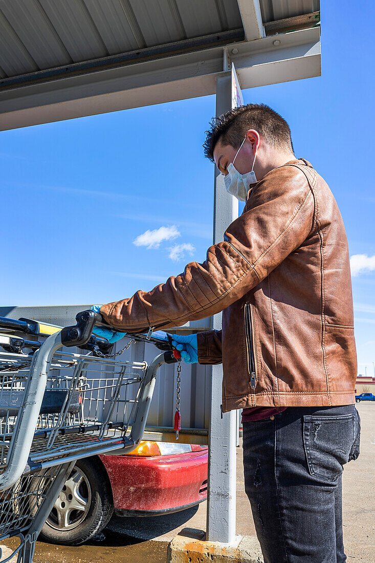 A young man gets a grocery cart during the Covid-19 World Pandemic; Edmonton, Alberta, Canada