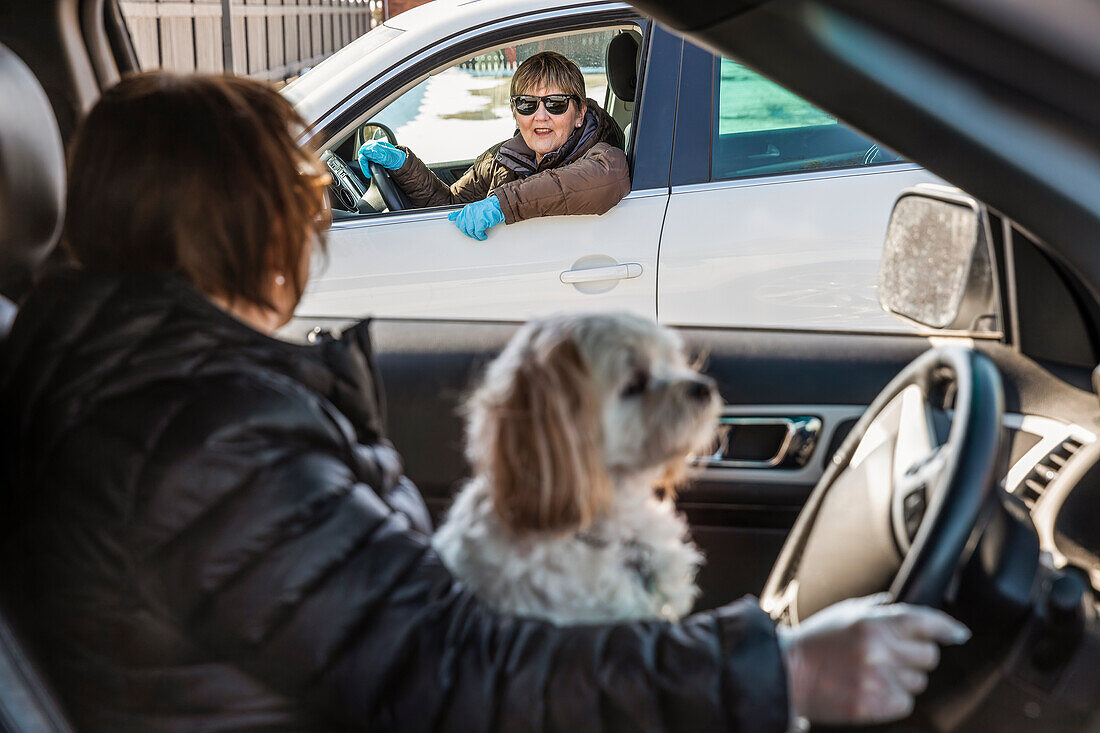 Zwei Frauen treffen sich während der Covid-19-Weltpandemie in der Nachbarschaft und entfernen sich auf der Straße von ihren Fahrzeugen; St. Albert, Alberta, Kanada