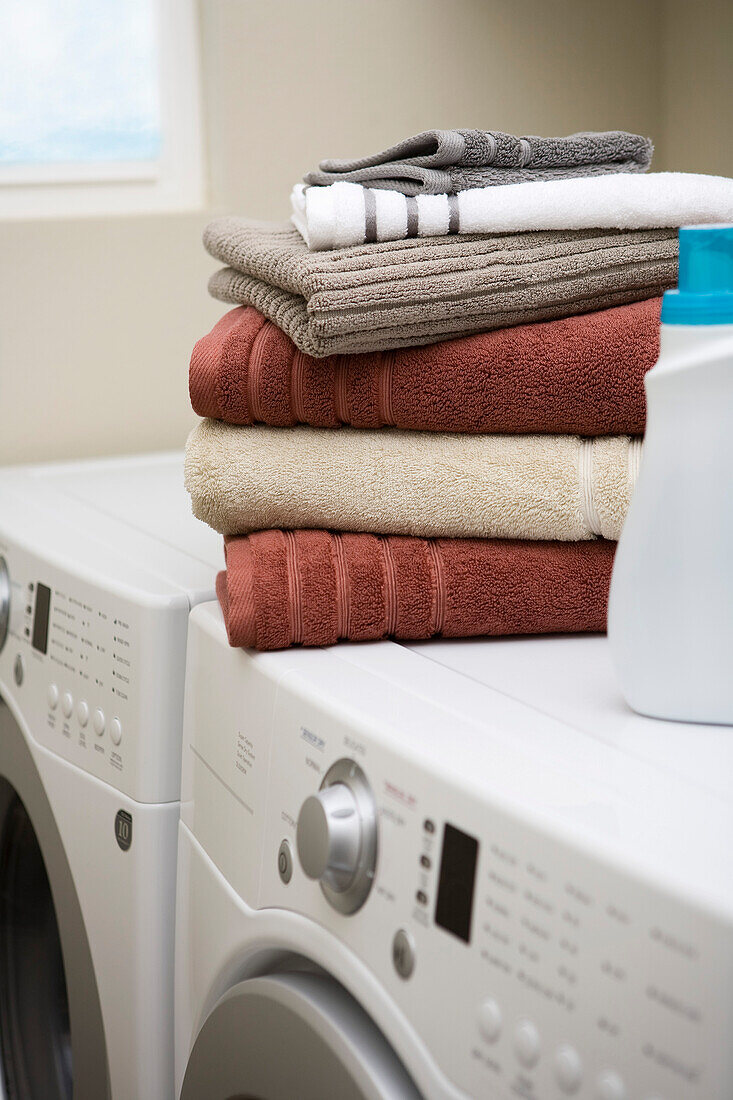 Stapel mit sauberen Handtüchern auf Waschmaschine und Trockner