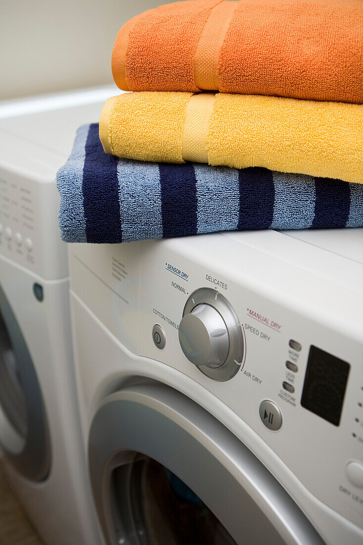 Stapel von Handtüchern auf Waschmaschine und Trockner