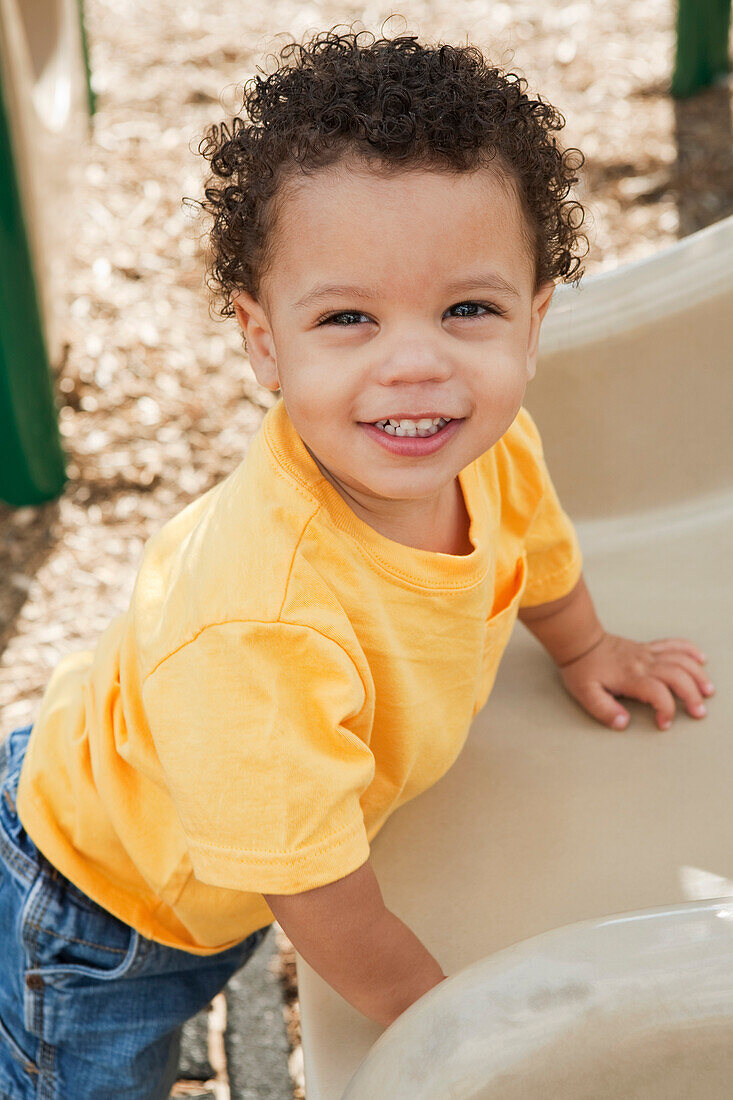 Portrait of Young Boy Standing at Bottom of Slide at Playground