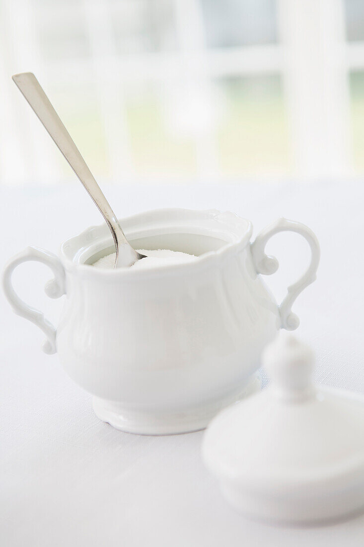 White porcelain sugar bowl with sugar and spoon, studio shot