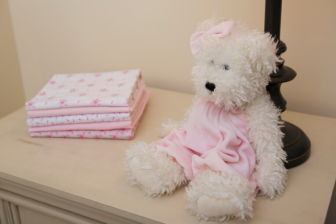 Stack of Baby Blankets on Dresser next to Teddy Bear and Lamp in Nursery