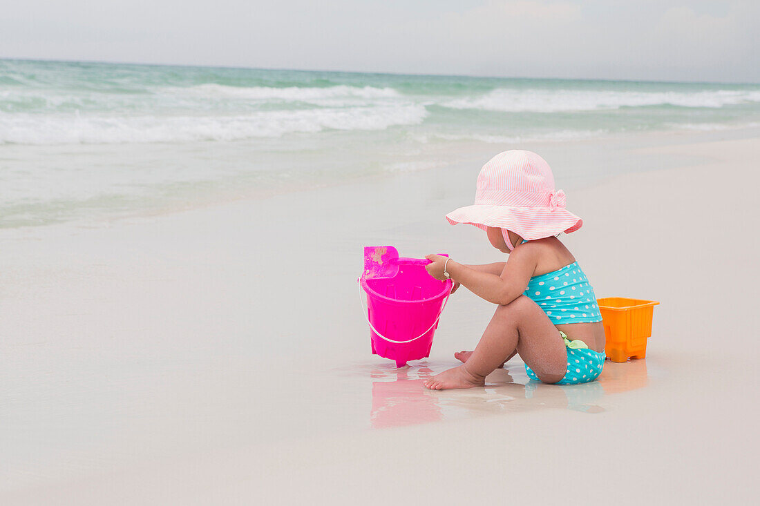 Toddler Girl Playing with Shovel and Bucket in Sand on Beach, Destin, Florida, USA