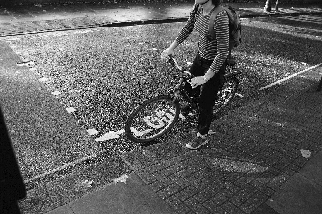 Frau auf Straße mit Fahrrad, London, England