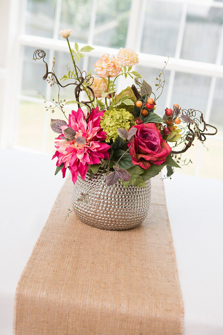 Floral centerpiece on table with burlap table runner
