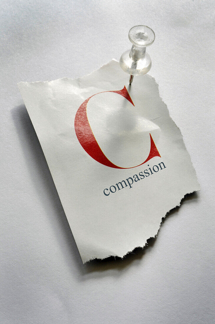 Close-up of Torn Page with C and Compassion on it, Pinned to Board