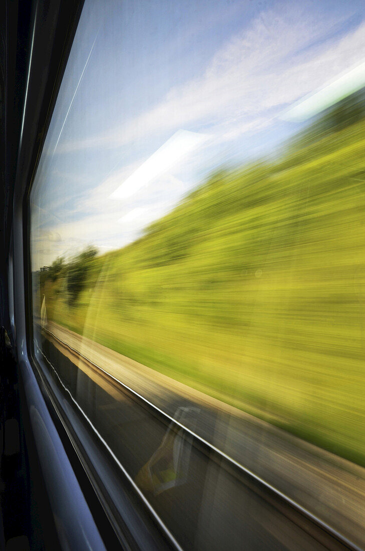 Blick aus dem Fenster eines rasenden Zuges auf dem Land