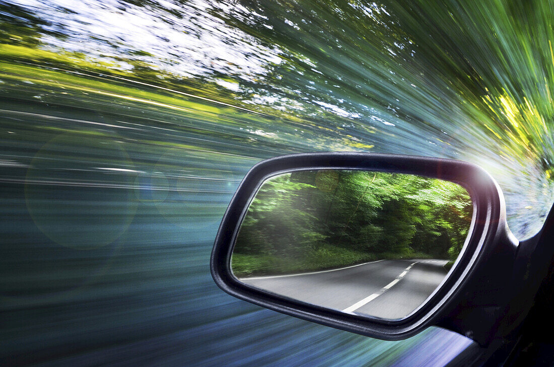 Blick auf die Straße, reflektiert im Fahrerspiegel eines Autos