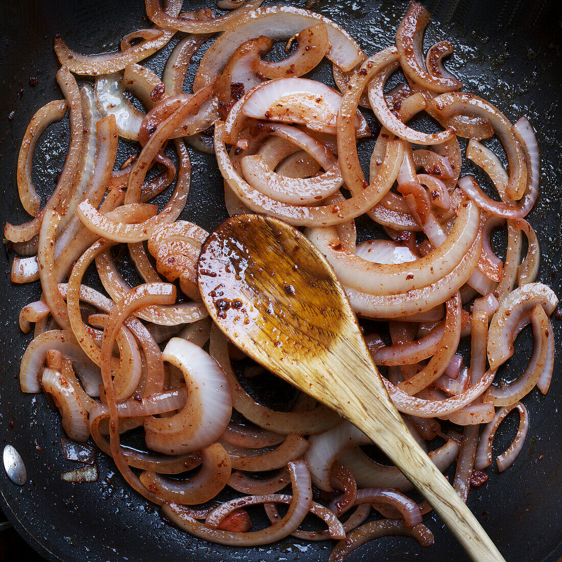 Overhead View of Frying Red Onions in Frying Pan and Wooden Spoon