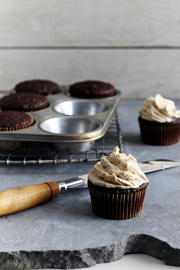 Frosting freshly made cupcakes, studio shot