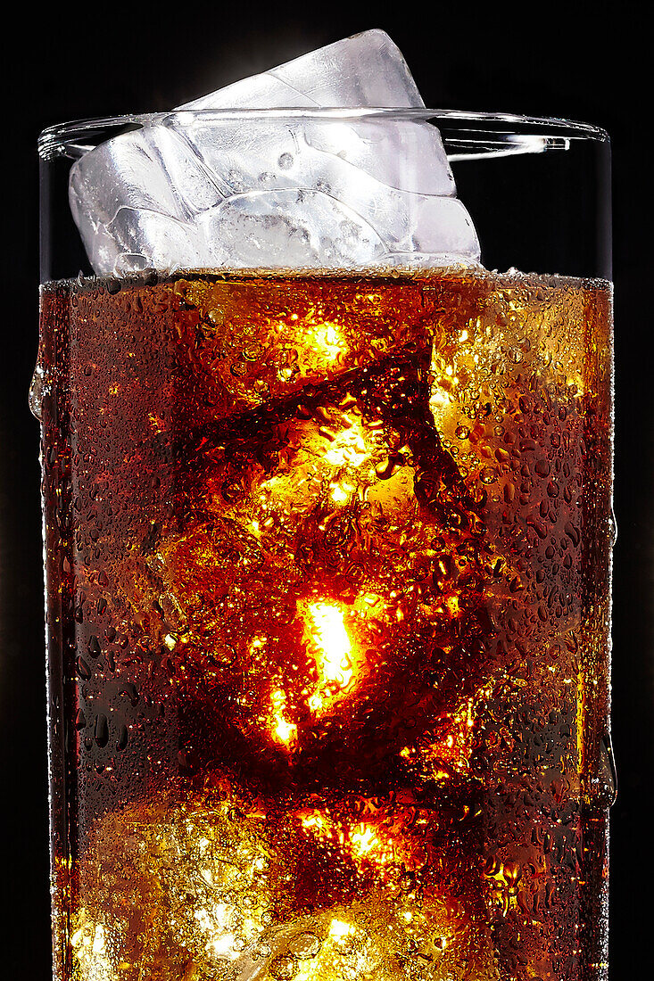 Glas Soda mit Eiswürfeln auf schwarzem Hintergrund