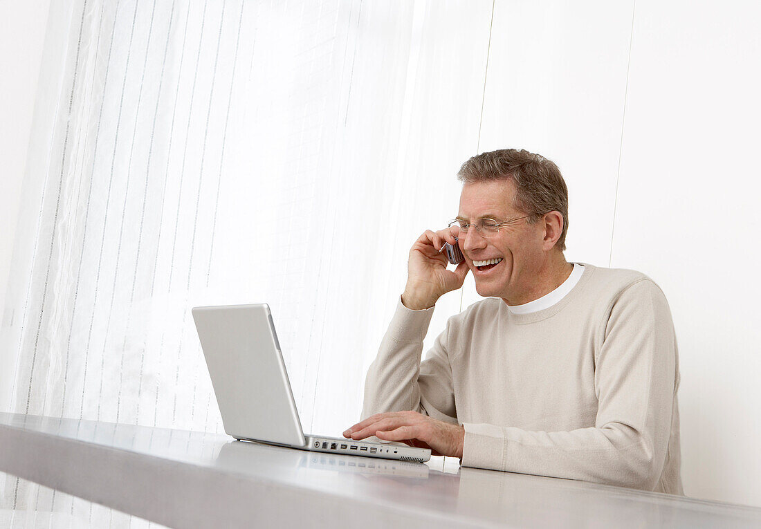 Mann mit Laptop und Mobiltelefon