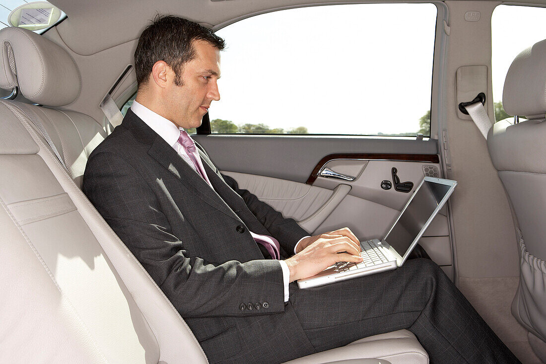 Geschäftsmann mit Laptop-Computer im Auto