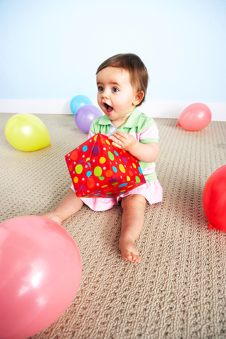 Baby Girl öffnet Geburtstagsgeschenk