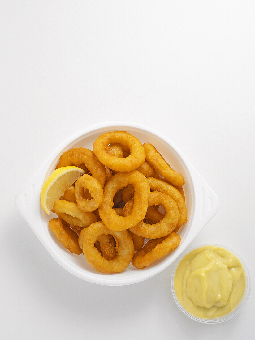 Fried calamari in bowl with condiment on white background, studio shot