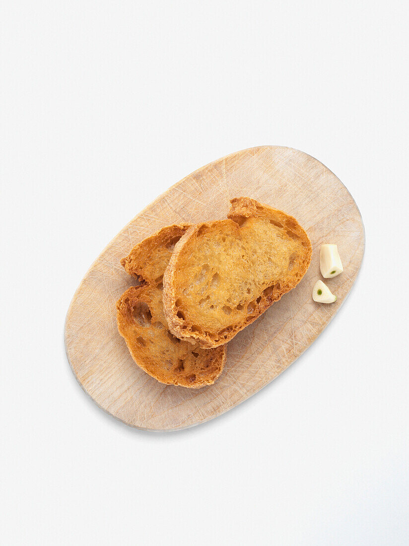 Crostini with garlic on wooden cutting board, on white background, stuadio shot